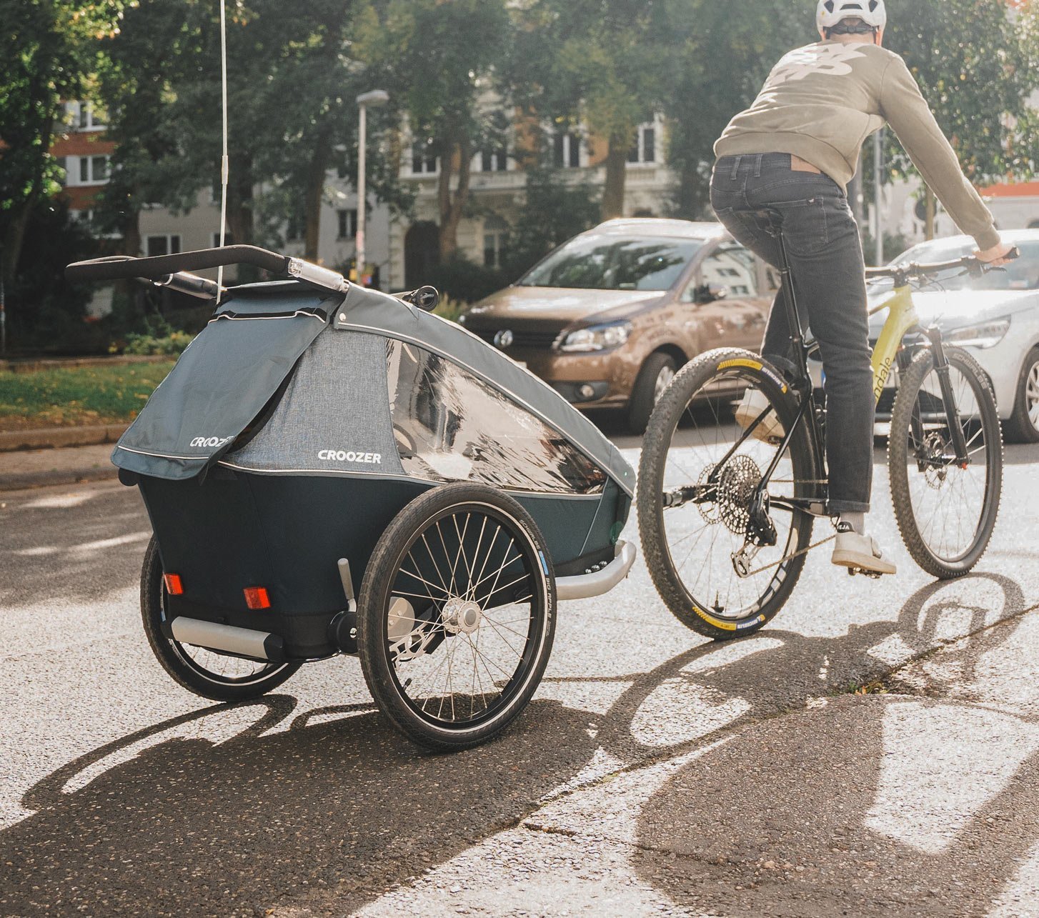 Tim von bc fährt mit seinem Rad und dem Croozer Kid Vaaya Kinderanhänger durch die Stadt.