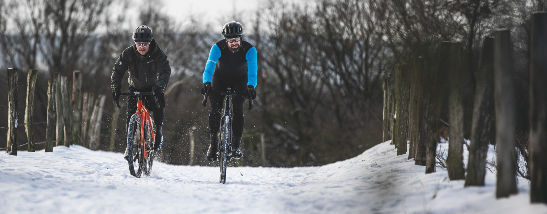 Zwei Männer fahren Gravel-Bikes im Schnee.