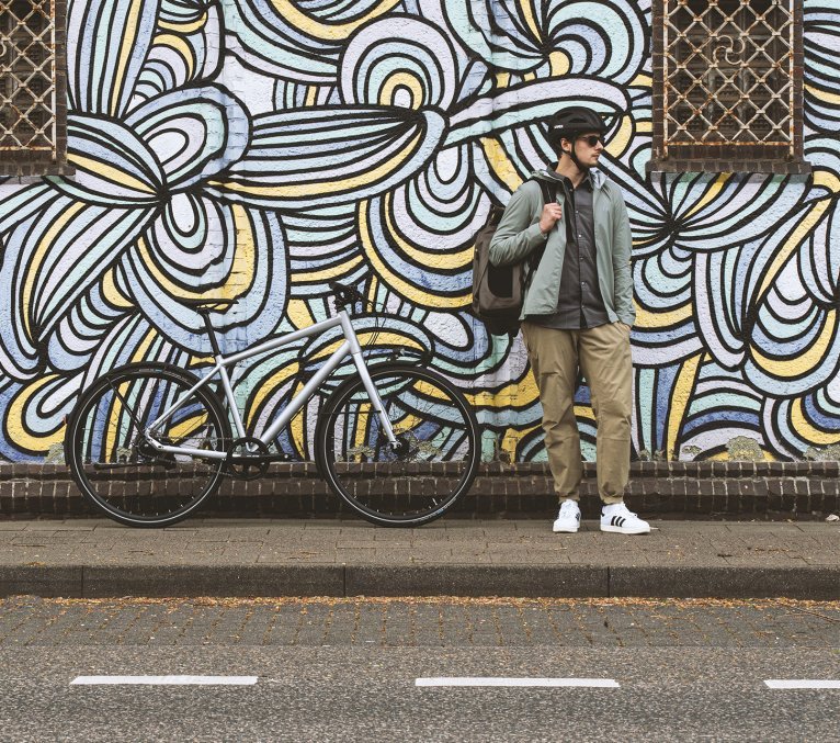 Bicycle commuter stands in front of an eye-catching graffiti wall in an urban environment