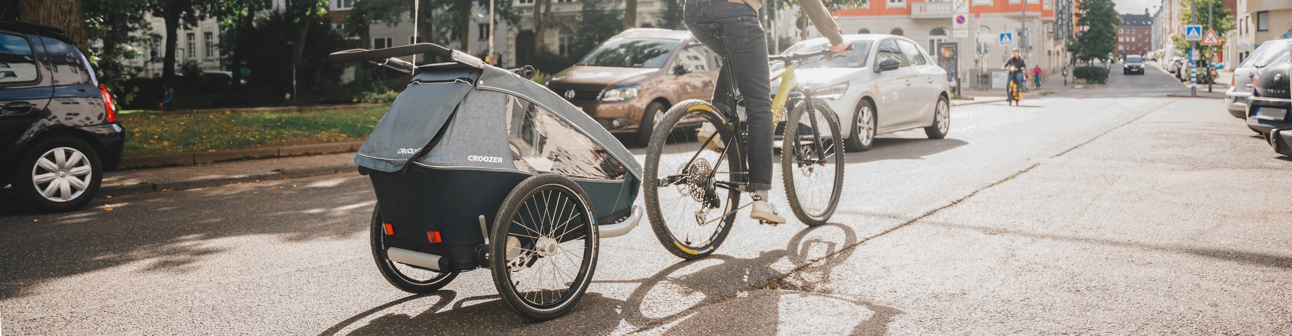 Tim von bc fährt mit seinem Rad und dem Croozer Kid Vaaya Kinderanhänger durch die Stadt.