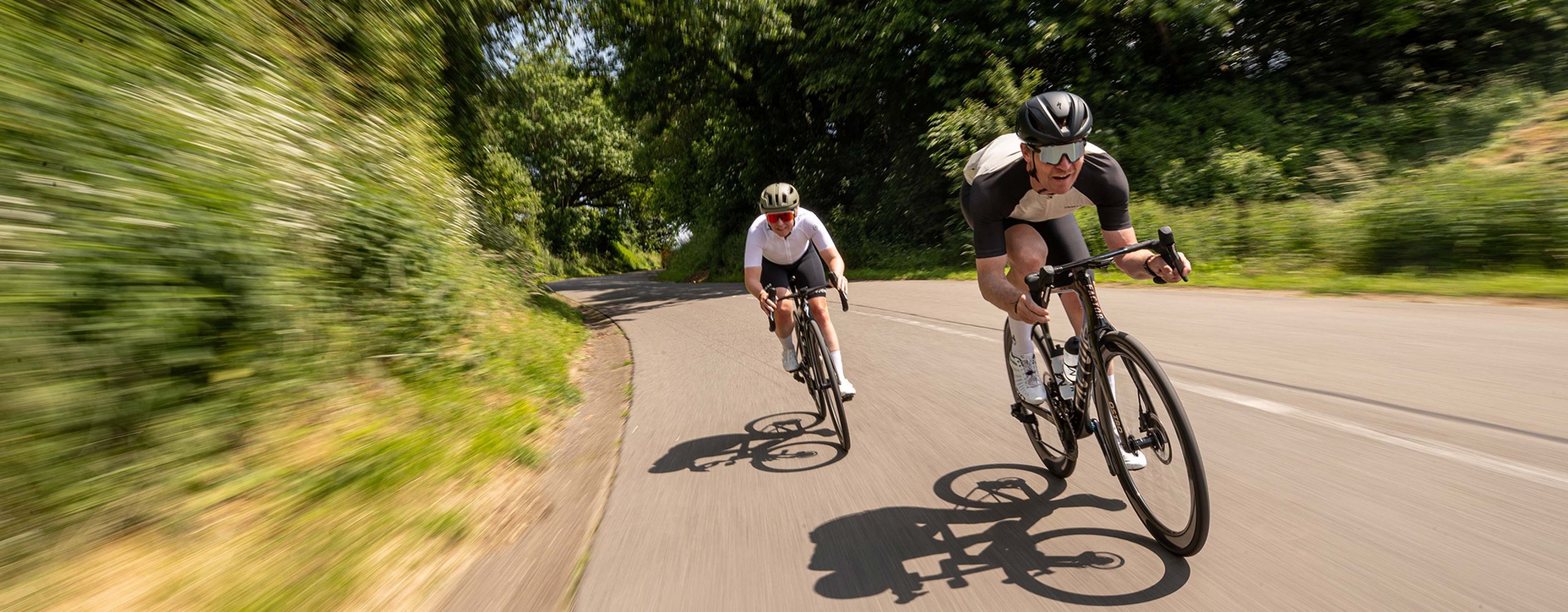 Rennradfahrer Pärchen rasen mit ihren Fahrrädern die Straße entlang