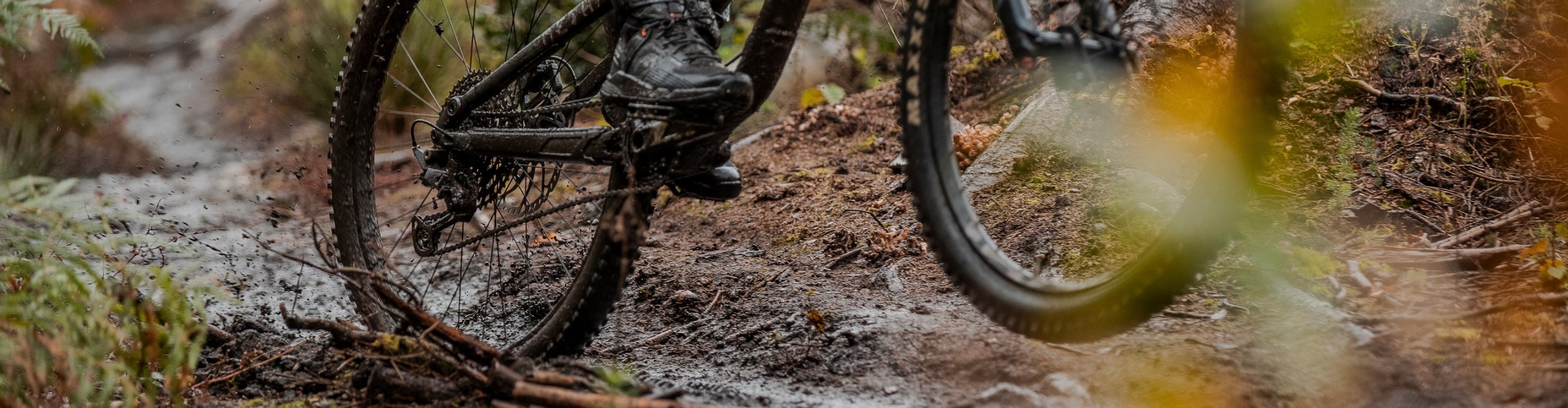 Detail von Mountainbikerifen die durch schlammiges Gelände fahren