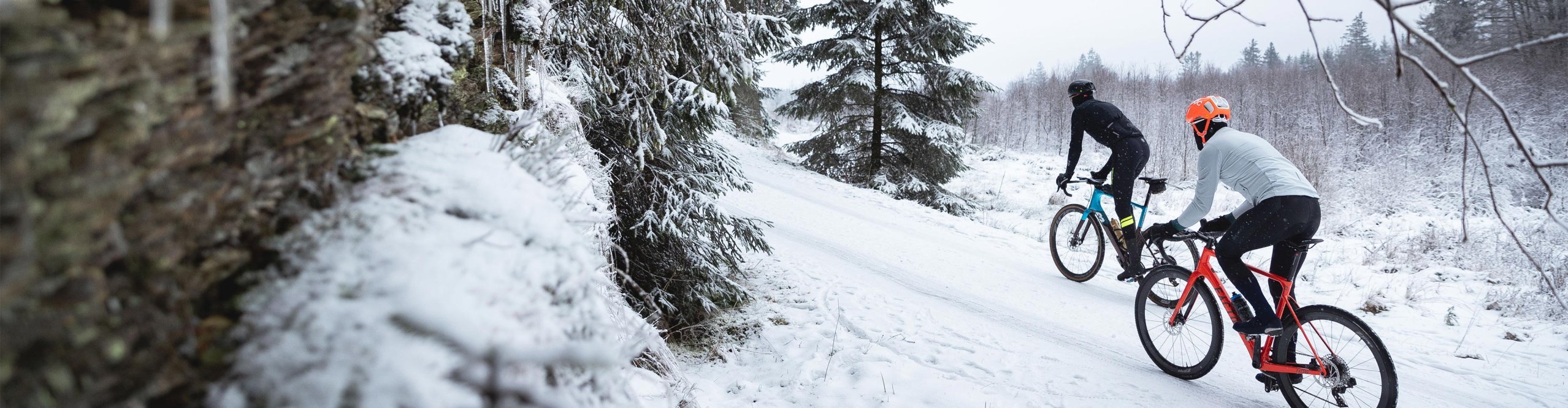 Zwei Gravel Biker fahren durch einen schneebedeckten Wald