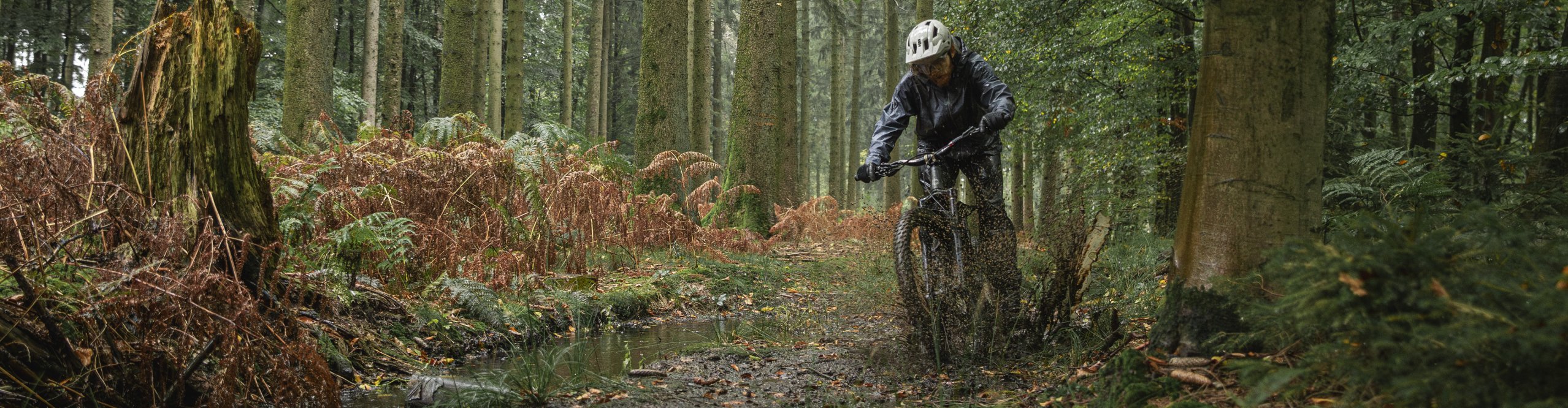 Arno von bike components fährt mit seinem Moutainbike durch schlammige Waldpfützen