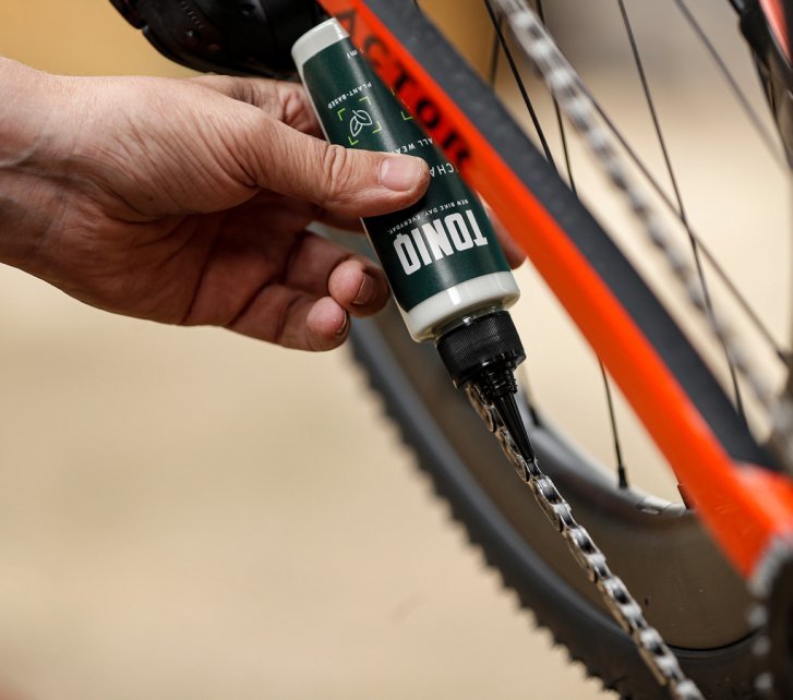 De la cire pour chaîne TONIQ est appliquée sur une chaîne de vélo. 