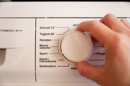 Le sélecteur de programme d'une machine à laver. Une main règle le programme sport.