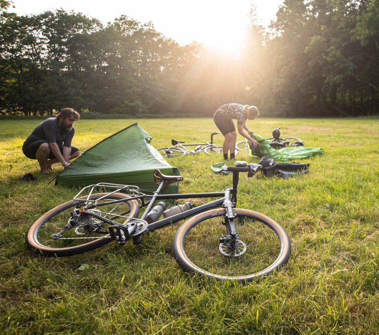 Gravelbiker schlagen ihre Zelte bei ihrem Bikepacking Trip auf.