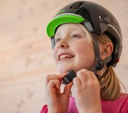 Une fille blonde touche la sangle du menton d’un casque de vélo noir.