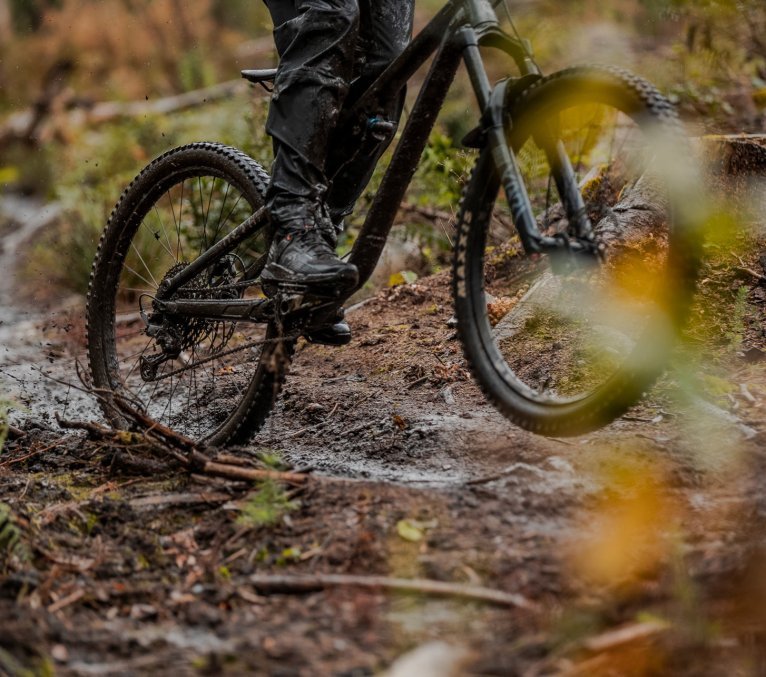 Detail von Mountainbikerifen die durch schlammiges Gelände fahren