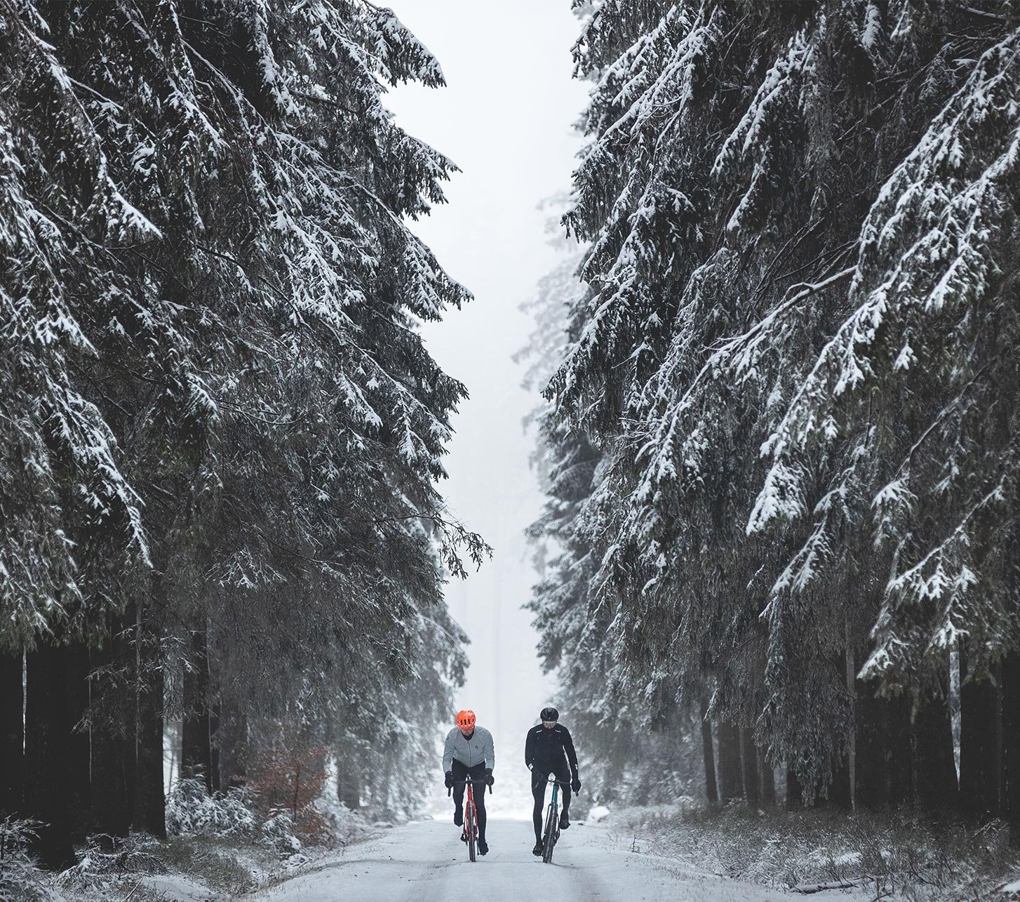 Zwei Gravelbiker fahren über schneebedeckte Wald- und Schotterwege