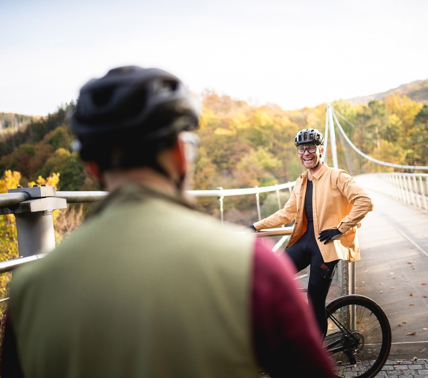 Gravel Bekleidung Markus und Björn stehen in Gravelmontur vor einer Hängebrücke in der herbstlichen Eifel