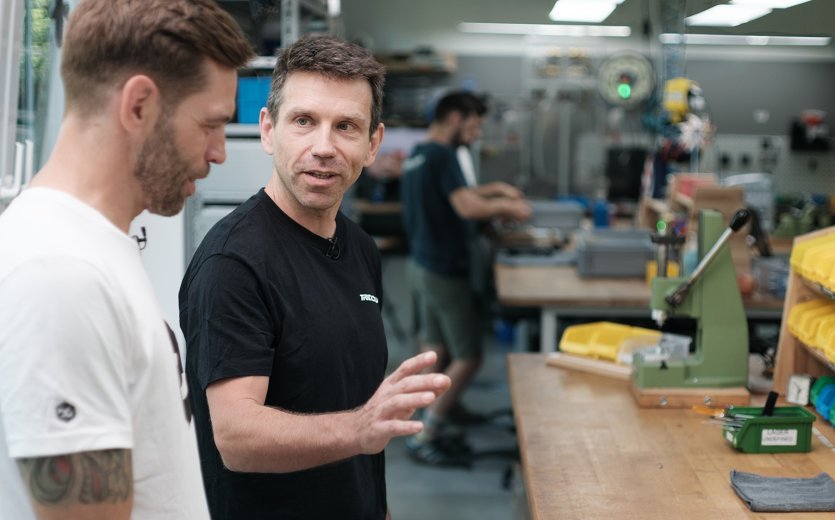 Rainer de bike-components avec un membre de l'équipe Trickstuff présentant le frein assemblé, symbole d'une collaboration étroite.