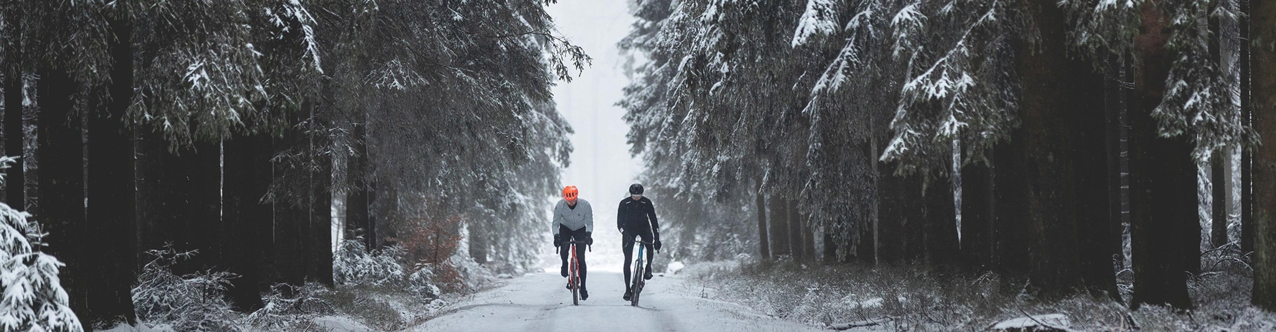 Zwei Gravelbiker fahren über schneebedeckte Wald- und Schotterwege