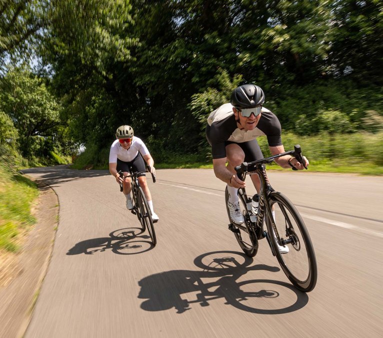 Rennradfahrer Pärchen rasen mit ihren Fahrrädern die Straße entlang