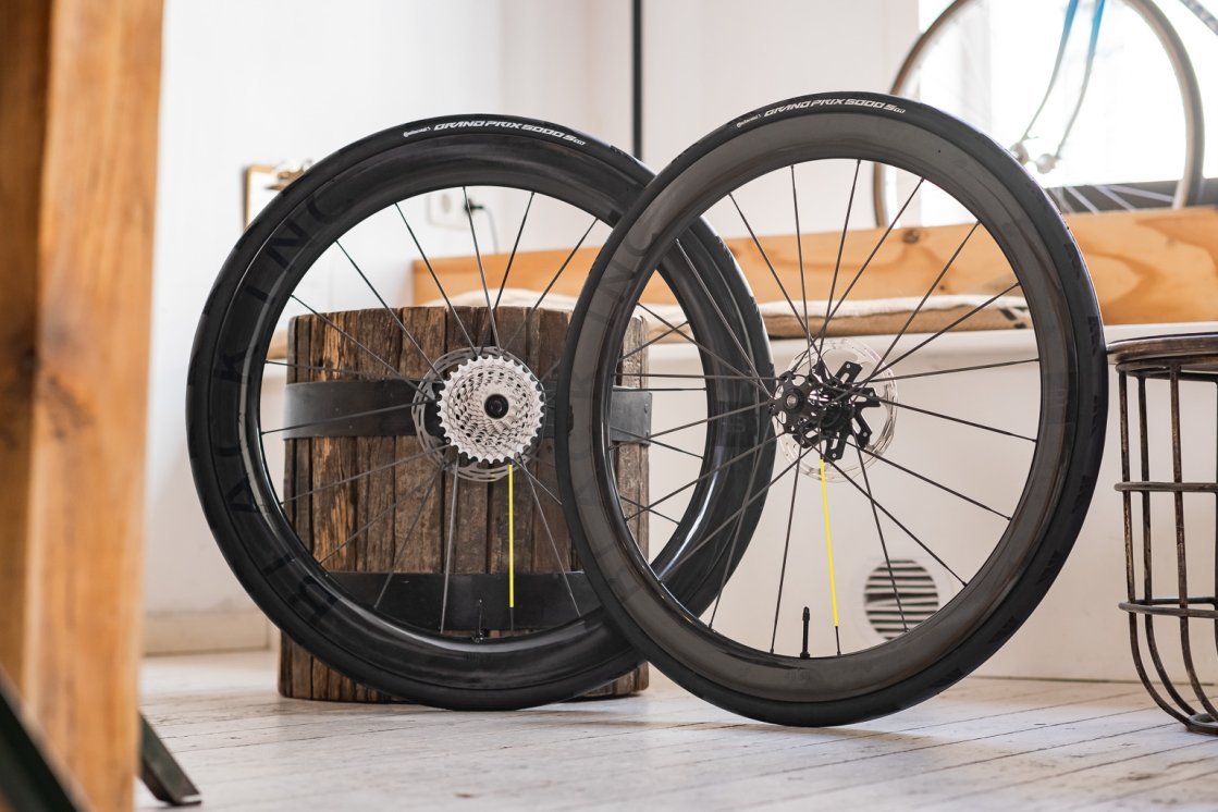 Two Black Inc carbon road bike wheels leaning in a bright, cozy showroom.