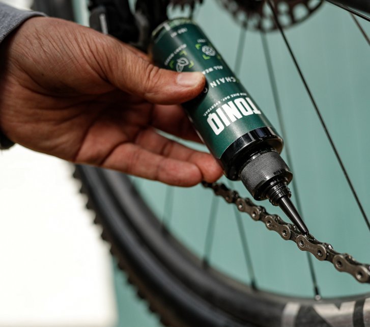 De l'huile pour chaîne TONIQ est appliquée sur une chaîne de vélo. 