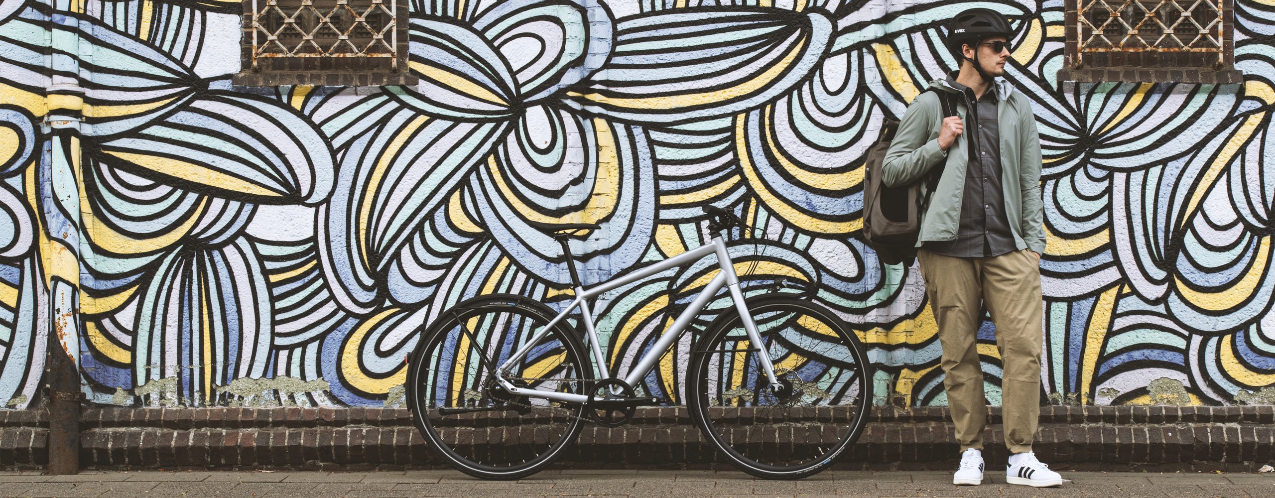 Bicycle commuter stands in front of an eye-catching graffiti wall in an urban environment