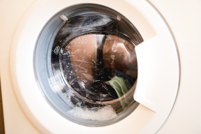 Une charge de linge fonctionnel dans une machine à laver. À travers le couvercle en verre, on peut voir à l’intérieur du tambour.