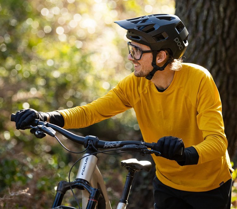 Mountainbiker mit sommerlichen gelben MTB Trikot schiebt sein Bike