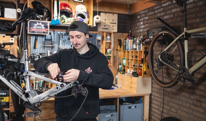 bc Mechanic Pascal checks the rear brake of a RAAW mountain bike in an at-home workshop.