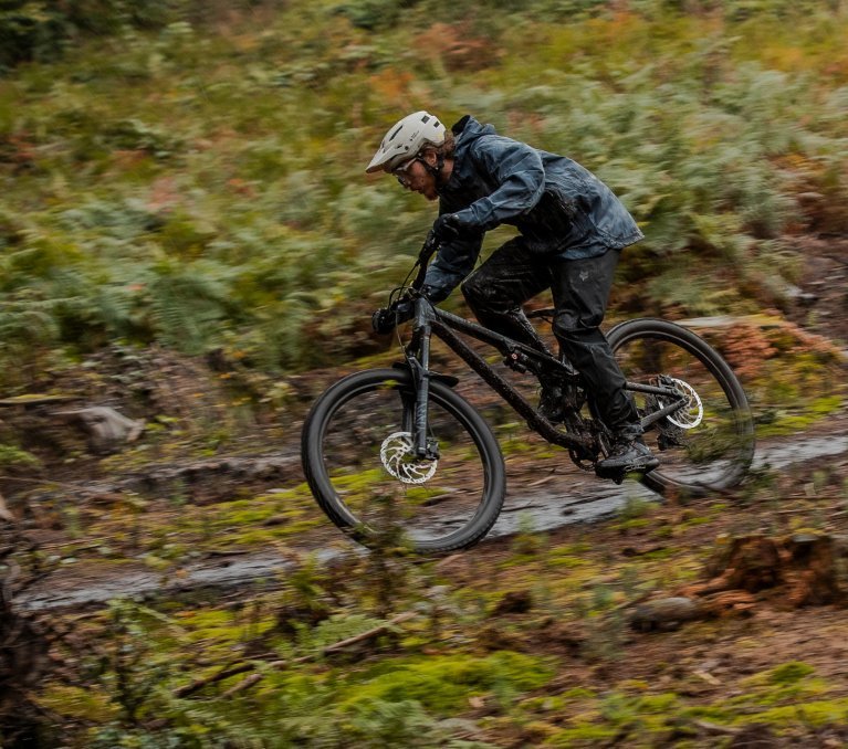 Arno von bike components fährt mit seinem Moutainbike durch schlammige Waldpfützen