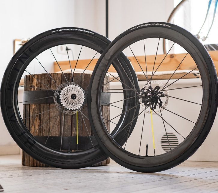 Two Black Inc carbon road bike wheels are leaning in a bright, cozy showroom.